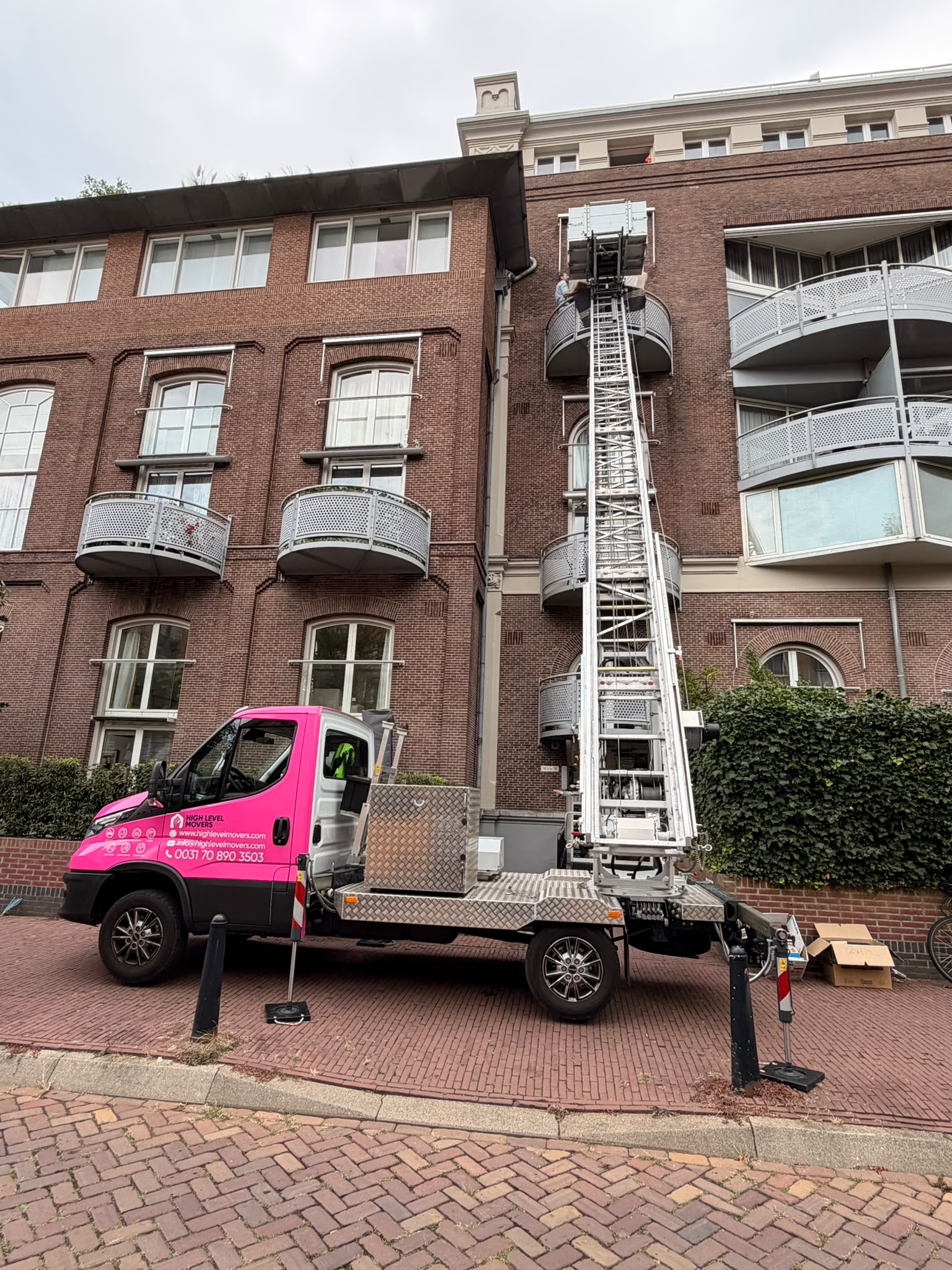Roze verhuislift aan het werk in Den Haag, meubels omhoog liften naar een hoge etage