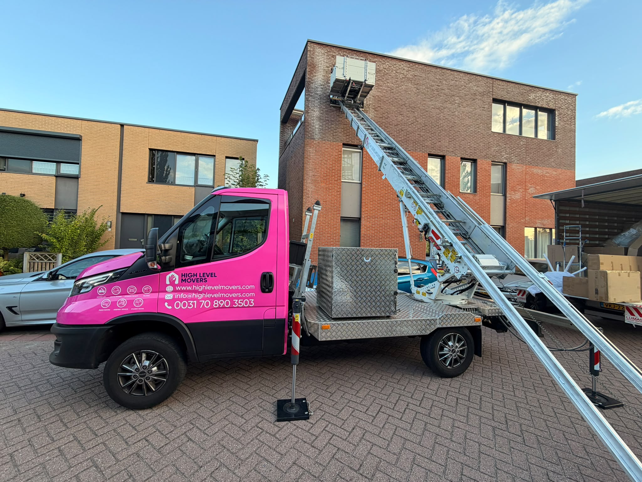 Zijaanzicht van onze opvallende roze verhuislift wagen klaar voor gebruik